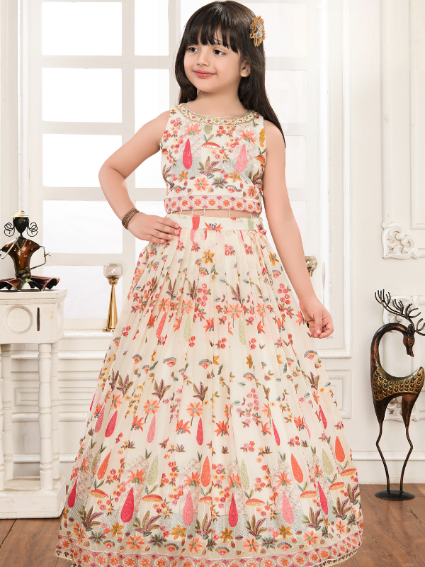 Young girl modeling a voluminous cream/off-white ethnic set with a sleeveless crop top and full skirt, both covered in colorful floral embroidery.