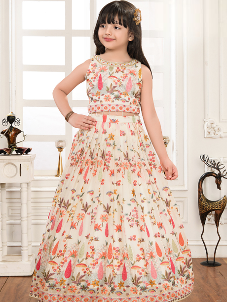 Young girl modeling a voluminous cream/off-white ethnic set with a sleeveless crop top and full skirt, both covered in colorful floral embroidery.