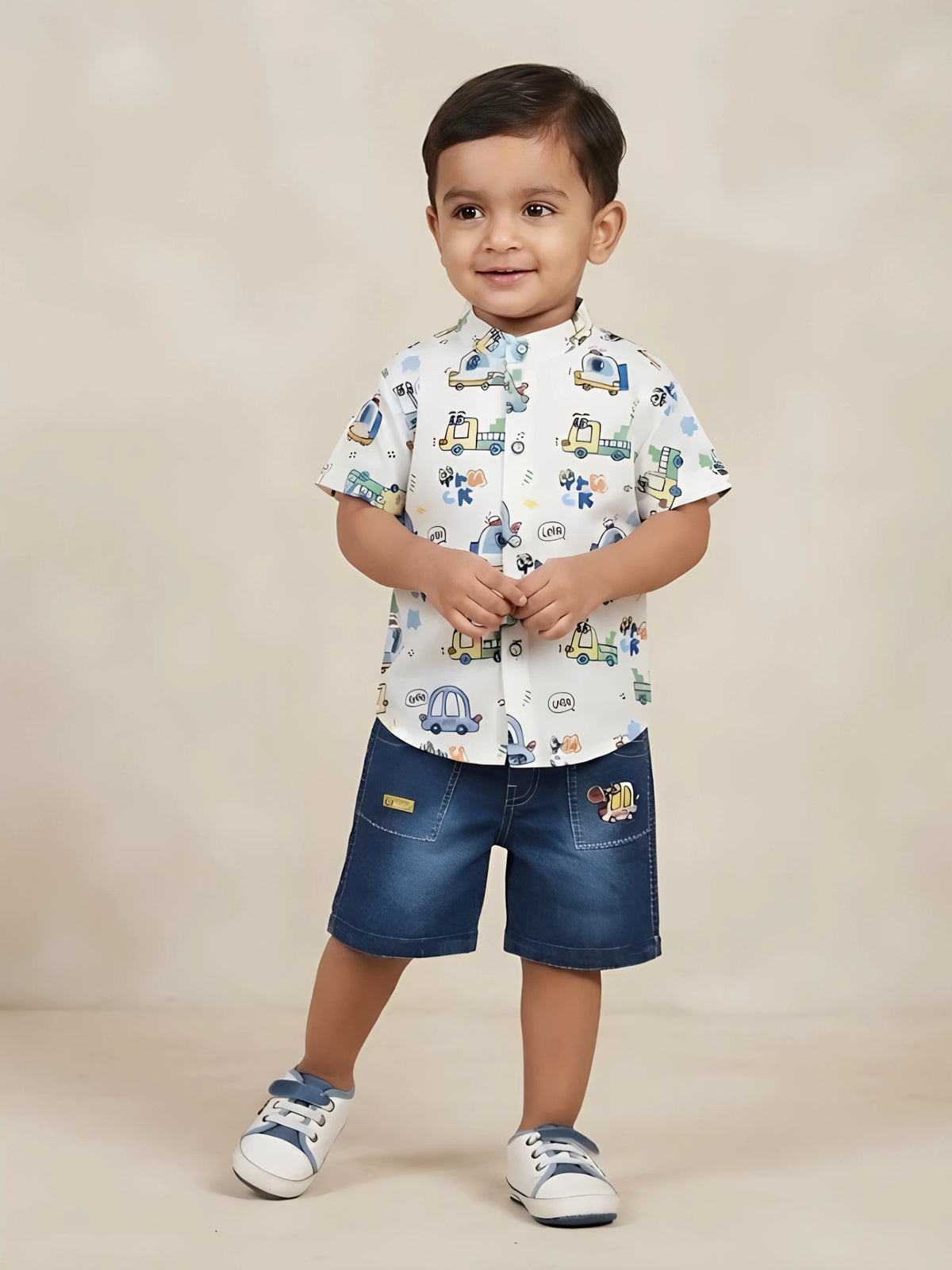 Boys white short-sleeve Mandarin collar shirt with vehicle print paired with blue denim shorts.