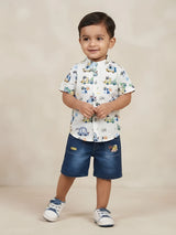 Boys white short-sleeve Mandarin collar shirt with vehicle print paired with blue denim shorts.