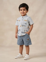 Young boy wearing a light blue half-sleeve car printed mandarin collar shirt with matching light blue shorts.