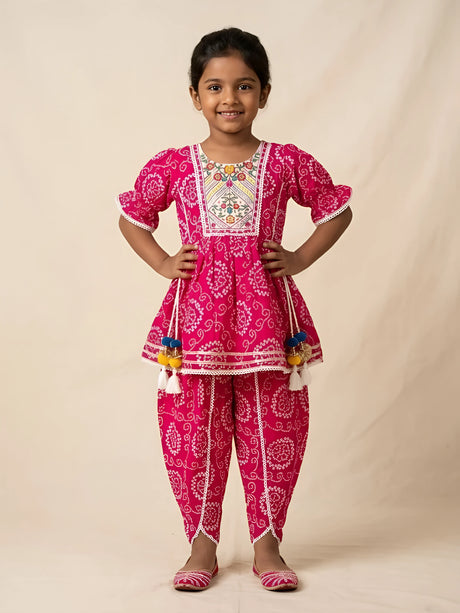 Young girl wearing a vibrant pink bandhani print kurti and matching dhoti pants set with embroidered neck yoke