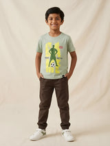 Young boy wearing a sage green short sleeve t-shirt featuring a football player graphic print, paired with brown trousers.