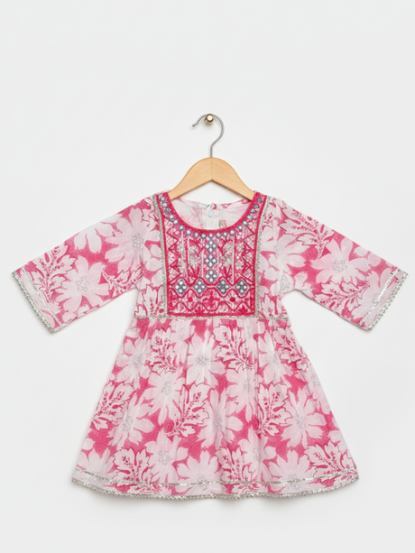Front view of a girls' 3/4 sleeve pink and white floral-printed peplum top (kurti) with a heavily embroidered and mirror-work detailed yoke, hanging on a wooden hanger.