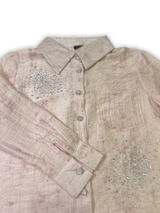 Front view of a girls' sheer peach long-sleeve button-up shirt with silver rhinestone clusters on the chest, hanging on a wooden hanger.