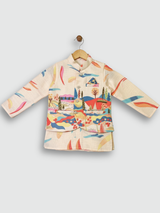 A young boy standing and smiling, wearing a cream long-sleeved kurta and pajama set with a sleeveless, brightly colored abstract-printed Nehru jacket.