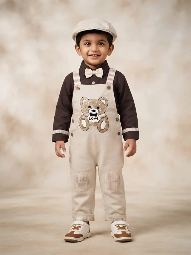 Boys wearing a cream dungaree with sequined teddy bear detail and dark shirt with bow tie
