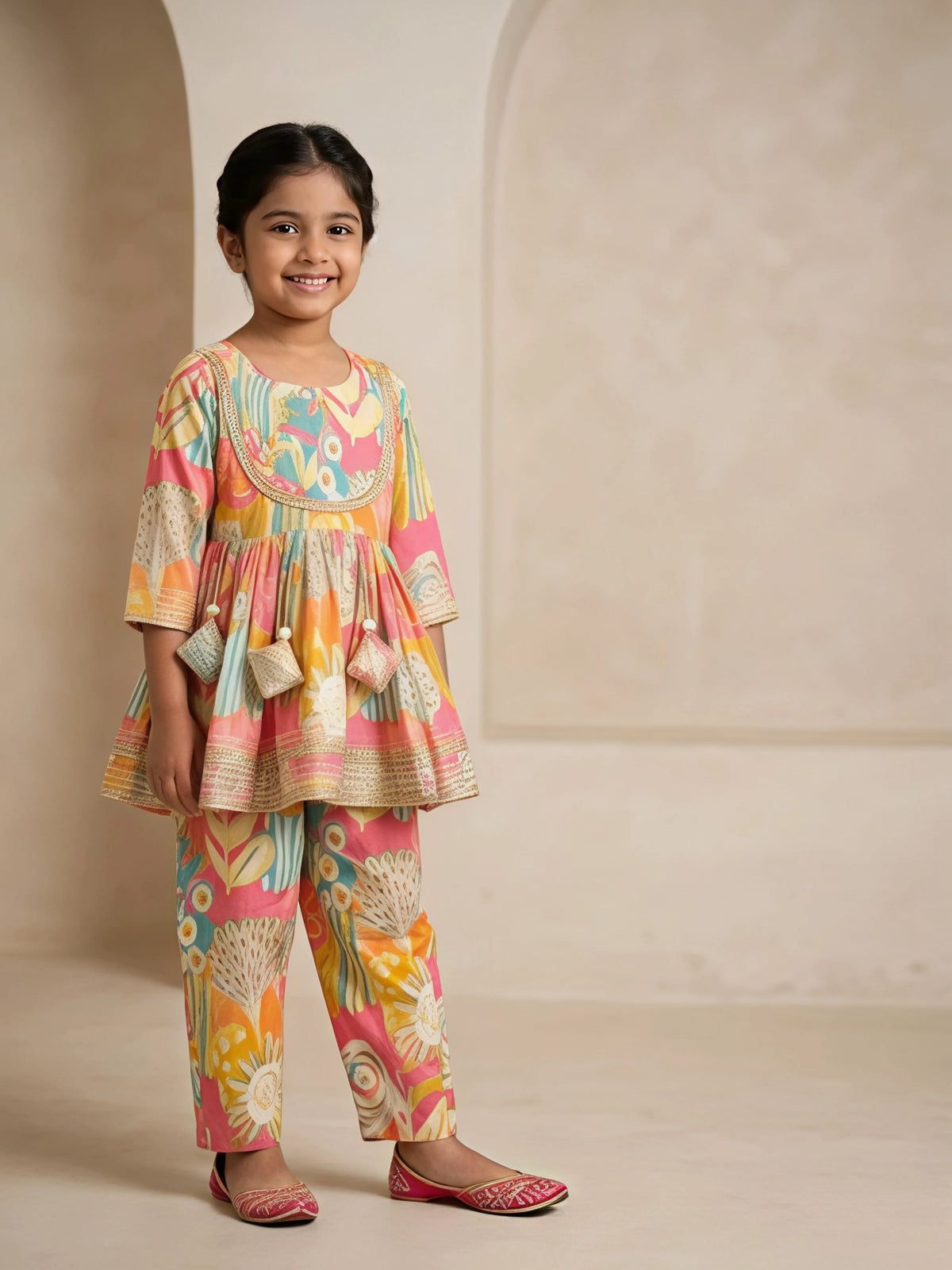 Young girl wearing a yellow and multi-color printed ethnic tunic top with matching pants and lace detailing.