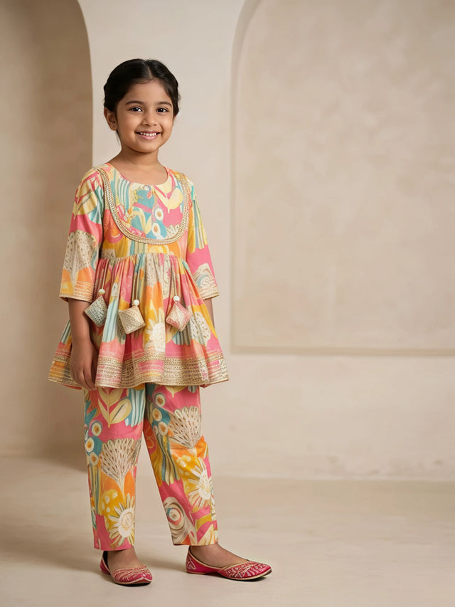 Young girl wearing a yellow and multi-color printed ethnic tunic top with matching pants and lace detailing.