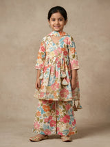 Young girl wearing a cream floral printed Angrakha style tunic with matching wide-leg sharara pants and dupatta