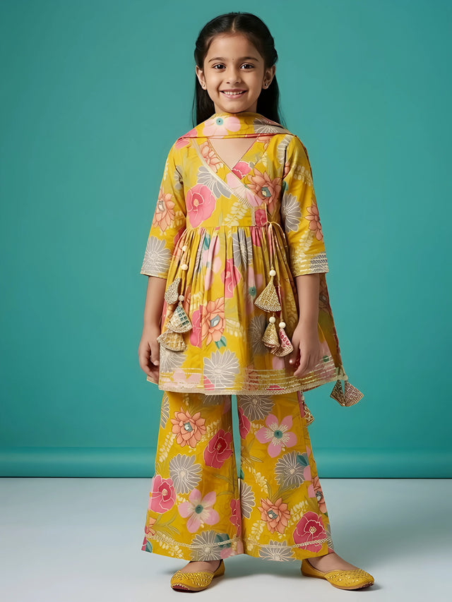 Girl wearing a green floral printed Angrakha kurti and flared sharara suit set with tassel details and matching dupatta