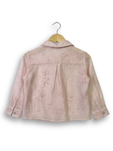 Front view of a girls' sheer peach long-sleeve button-up shirt with silver rhinestone clusters on the chest, hanging on a wooden hanger.