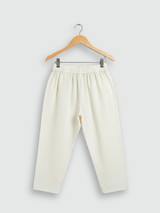 Boys' cream colored kurta with colorful all-over print of geometric and floral motifs, hanging on a wooden hanger.