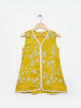 Front view of girls' wide-leg yellow palazzo pants with scattered white floral embroidery and a white lace trim on the hem, hanging on a wooden hanger.