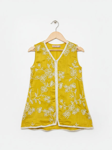Front view of girls' wide-leg yellow palazzo pants with scattered white floral embroidery and a white lace trim on the hem, hanging on a wooden hanger.