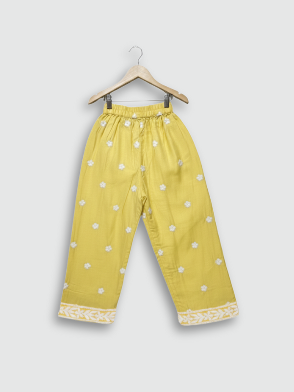 Full-length image of a young girl wearing a bright yellow, white-embroidered, flared frock (kurta) with matching yellow pants and a white dupatta.