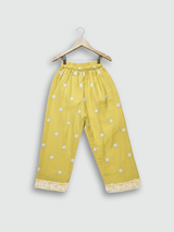 Full-length image of a young girl wearing a bright yellow, white-embroidered, flared frock (kurta) with matching yellow pants and a white dupatta.