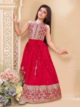 Young girl wearing a sleeveless deep red or magenta lehenga choli. The top is covered in gold and silver embroidery, and the skirt features a wide, heavily detailed gold zari and sequin border.
