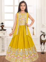 Young girl modeling a voluminous mustard yellow ethnic gown with a sleeveless embroidered jacket and heavy embroidery around the skirt's hem.
