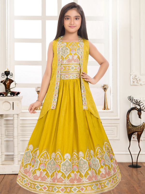 Young girl modeling a voluminous mustard yellow ethnic gown with a sleeveless embroidered jacket and heavy embroidery around the skirt's hem.