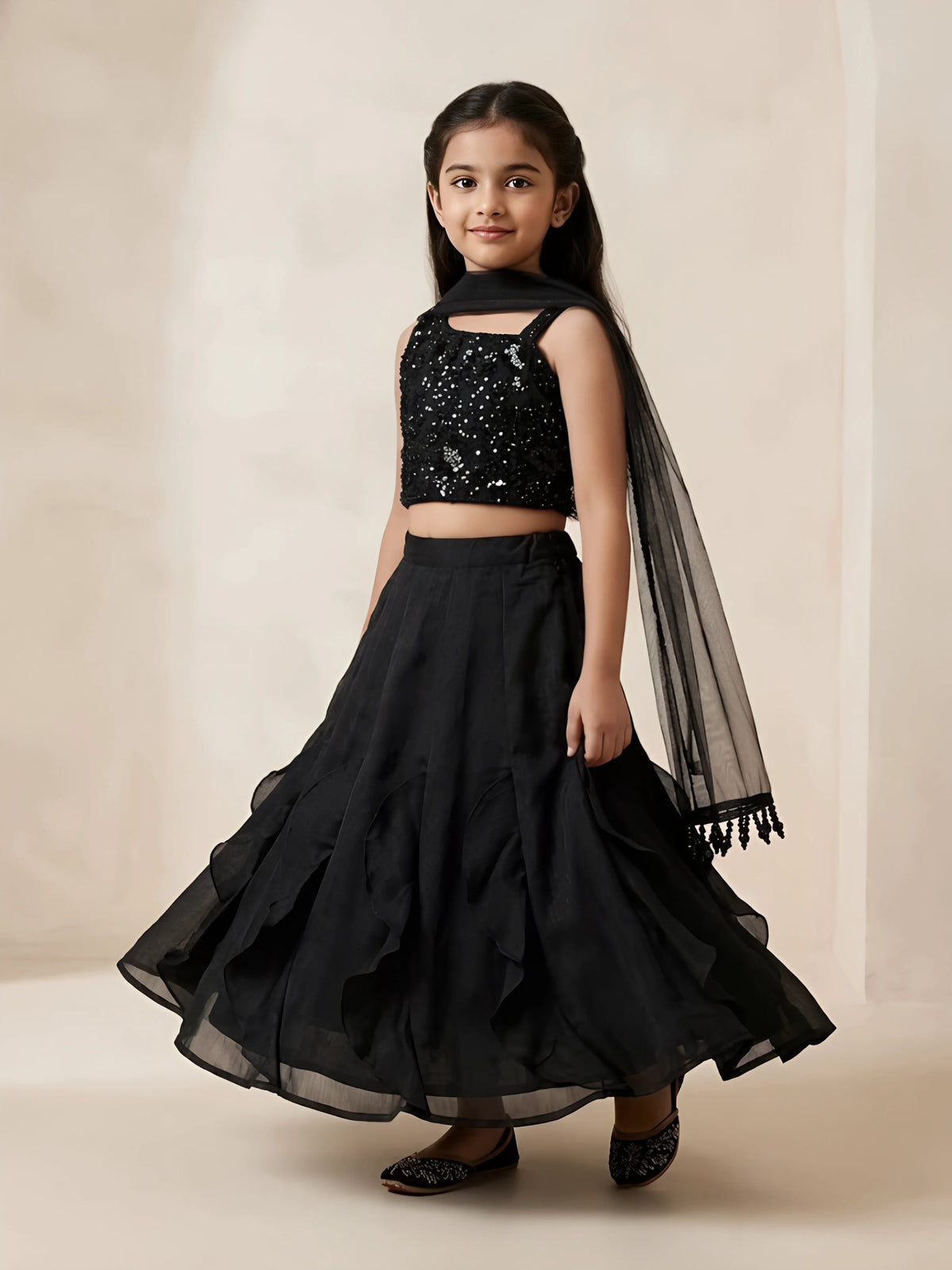 Girls black sequined choli set with sleeveless embroidered top, flared skirt, and black net dupatta.