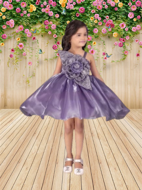 Young girl wearing a full-skirted, shimmering purple/lavender organza party frock with an asymmetrical one-shoulder strap and a large floral appliqué.