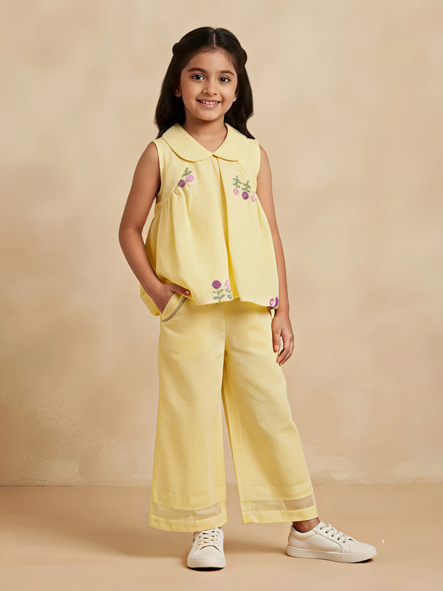 Girls yellow two-piece set featuring a sleeveless floral embroidered Peter Pan collar top and matching wide-leg trousers