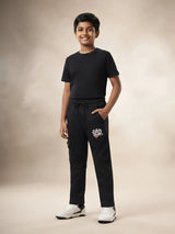 Young boy wearing black printed cargo trackpants with side pockets and a black t-shirt