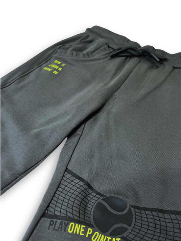 Boys' dark charcoal grey knit or fleece track pants with an elastic waist, pockets, and neon yellow "TENNIS" and tennis ball graphics on the legs.

Export to Sheets