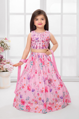 Young girl wearing a sleeveless light pink lehenga choli set with an all-over print of purple and pink flowers, featuring an embellished crop top.