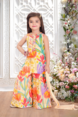 Young girl wearing a sleeveless cream sharara suit with a large, colorful floral print and bead embellishments on the neckline.