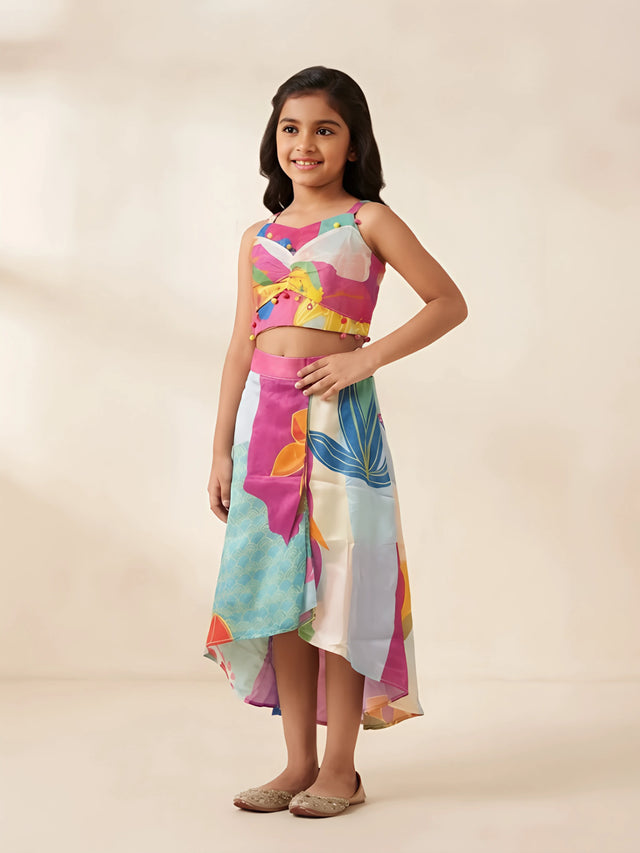 Girls rani multicolor printed crop top and high-low skirt set with pom pom details.