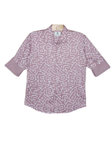 Young boy smiling in a cream/off-white collared shirt with small, whimsical adventure-themed embroideries, paired with dark brown/olive slim-fit trousers and white sneakers.