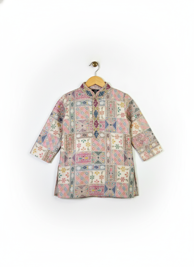 Boys' pink and multicolor geometric printed kurta with embellished neckline and three-quarter sleeves, paired with a cream pajama, hanging on separate hangers.