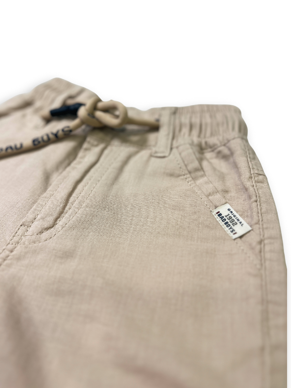 Boys' cream or pale khaki casual trousers with a comfortable elastic waistband, straight leg, and a thick, multicolored contrast rope drawstring.