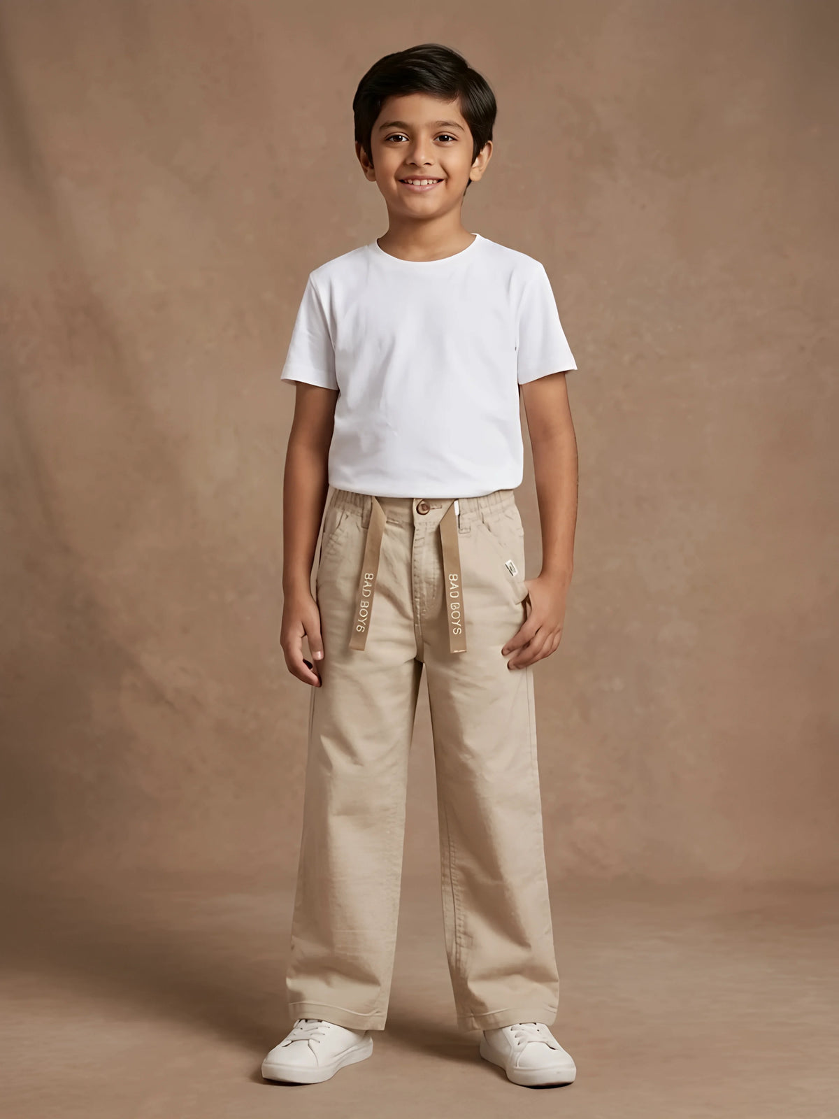 Young boy wearing cream casual trousers with front hanging tape design and a white t-shirt