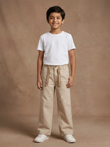Young boy wearing cream casual trousers with front hanging tape design and a white t-shirt