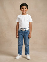 Young boy wearing stylish blue medium wash jeans with a white t-shirt and belt