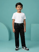 Young boy wearing classic black regular fit jeans styled with a white t-shirt and black sneakers against a light blue background.