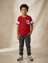 Front view of a red graphic print T-shirt for boys with white sleeve panels and henley neckline.