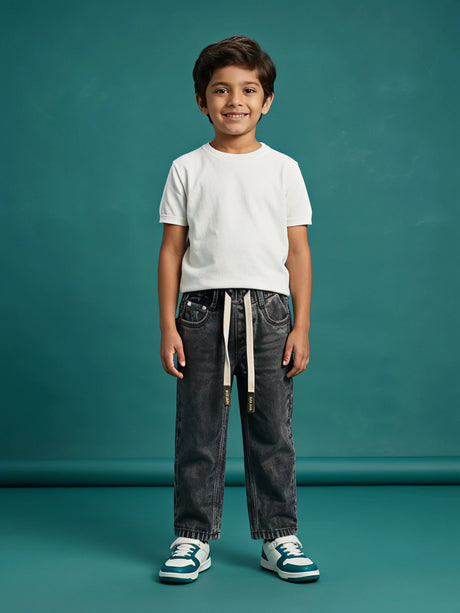 Young boy wearing grey washed loose fit drawstring jeans with a white t-shirt and sneakers