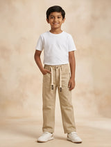 Young boy wearing cream casual pants with elastic drawstring waistband and white t-shirt