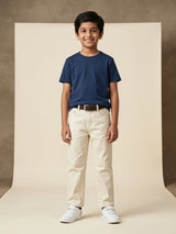 Young boy wearing off-white casual pants paired with a blue t-shirt and white sneakers