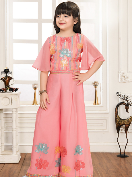 Young girl wearing a peach-colored two-piece set. The crop top has butterfly/bell sleeves and striped, sequined embroidery, paired with wide-leg palazzo pants featuring large floral embroidery near the hem.
