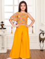 Young girl modeling a bright yellow ethnic set with a one-shoulder printed crop top and pleated wide-leg palazzo pants.