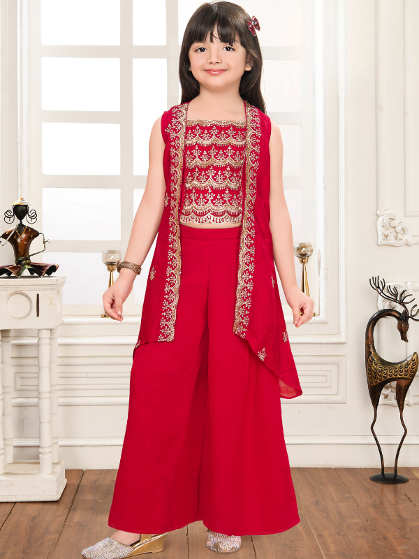 Young girl modeling a red ethnic set with an embroidered sleeveless crop top, a long vest/jacket, and full-length wide-leg palazzo pants.