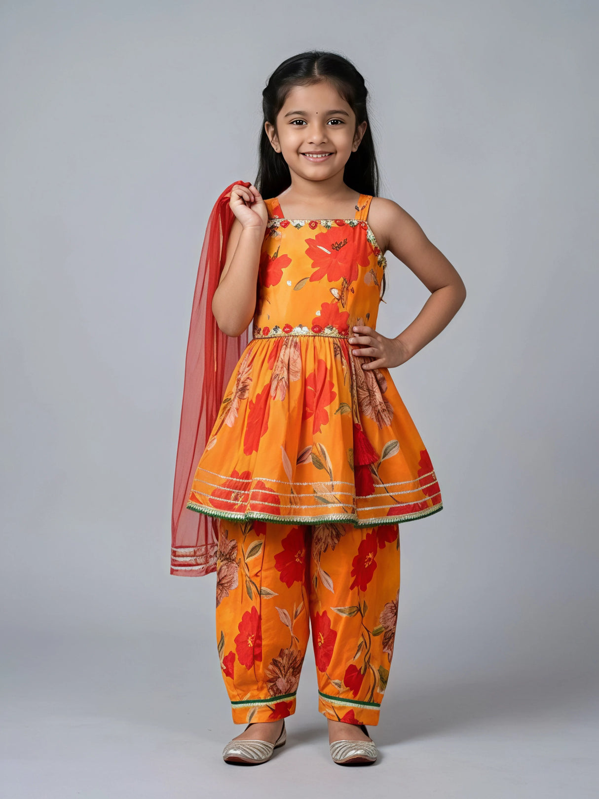 Young girl wearing bright orange floral printed Patiala suit set with red dupatta and gold trim details
