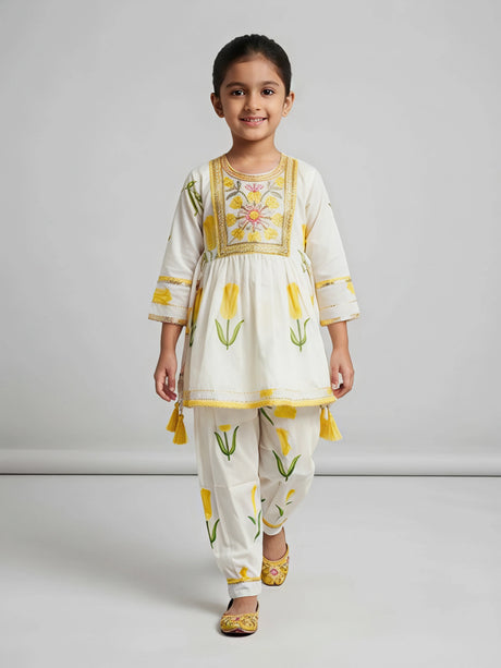 Young girl wearing a cream and yellow floral printed Patiala suit set with embroidery and side tassels