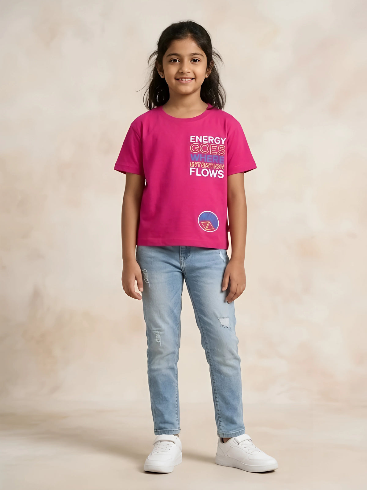 Young girl wearing a bright pink short-sleeve crew neck t-shirt with colourful graphic text print and light blue jeans.