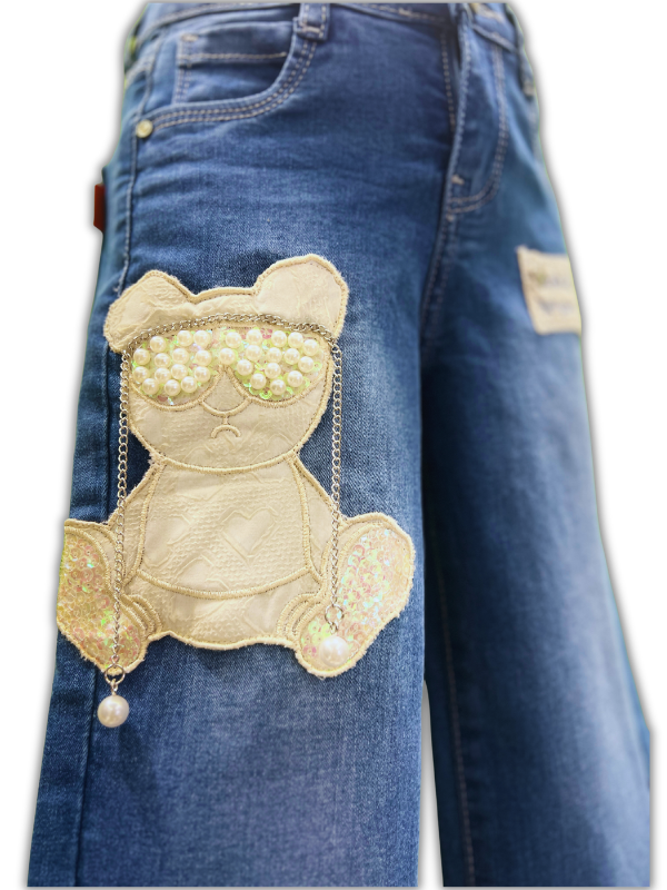 Girls' medium blue wash wide-leg denim jeans with an embroidered teddy bear patch decorated with pearls on the left leg, and a lace patch on the right.

Export to Sheets